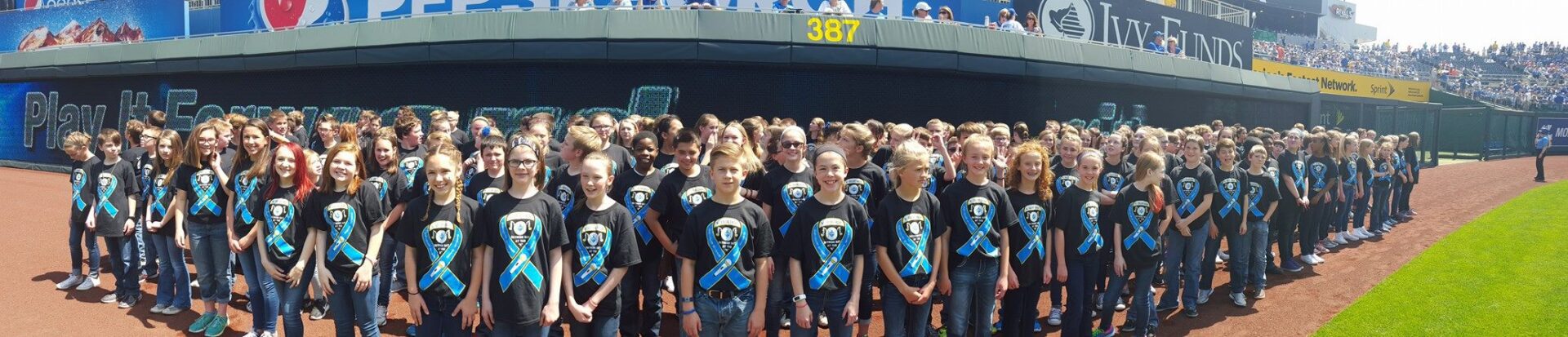 A group of children wearing blue ribbons on their shirts.