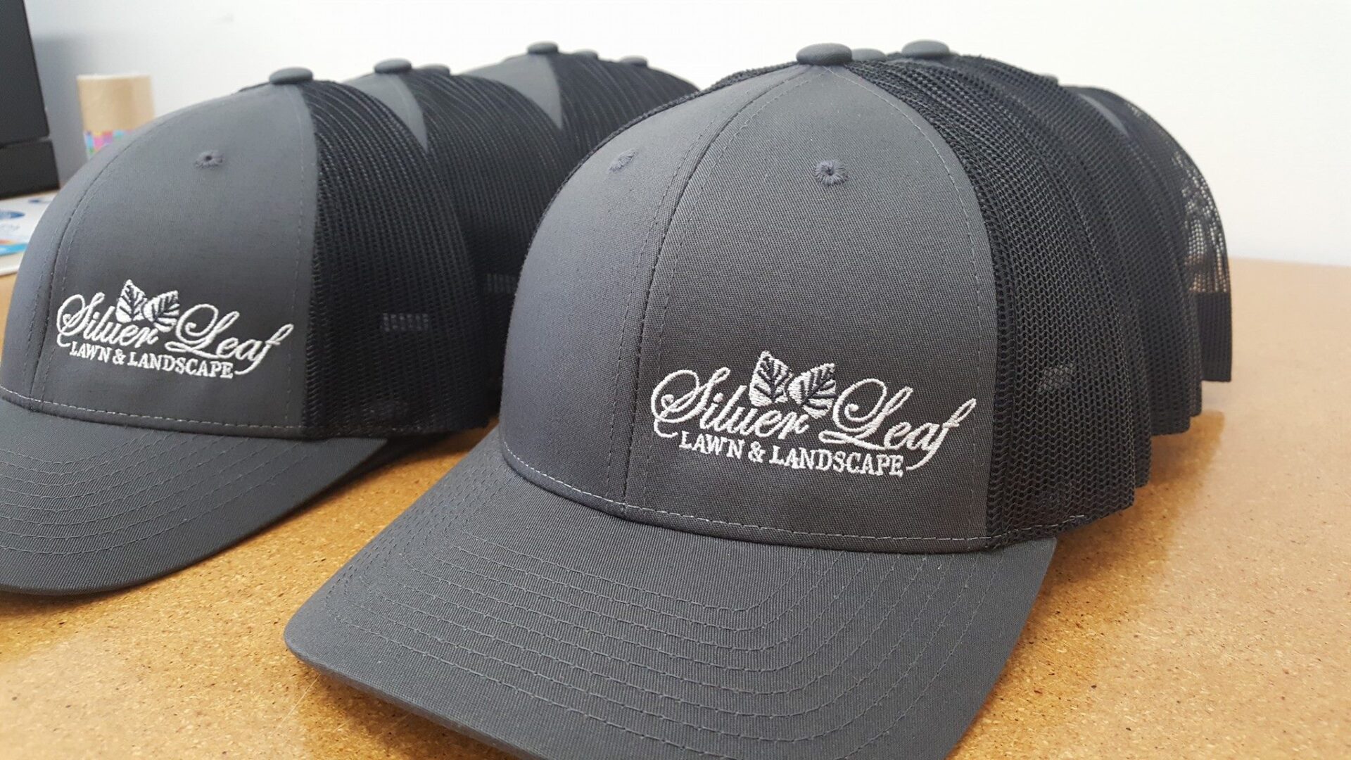 Silver Leaf Lawn and Landscape logo printed on black caps